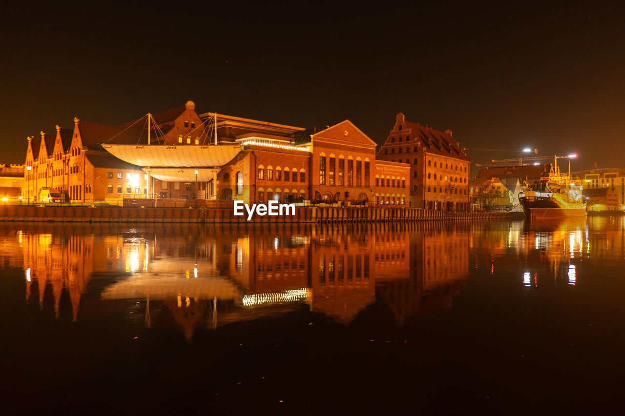 Old town in gdansk at night. the riverside on granary island reflection in moltawa river cityscape