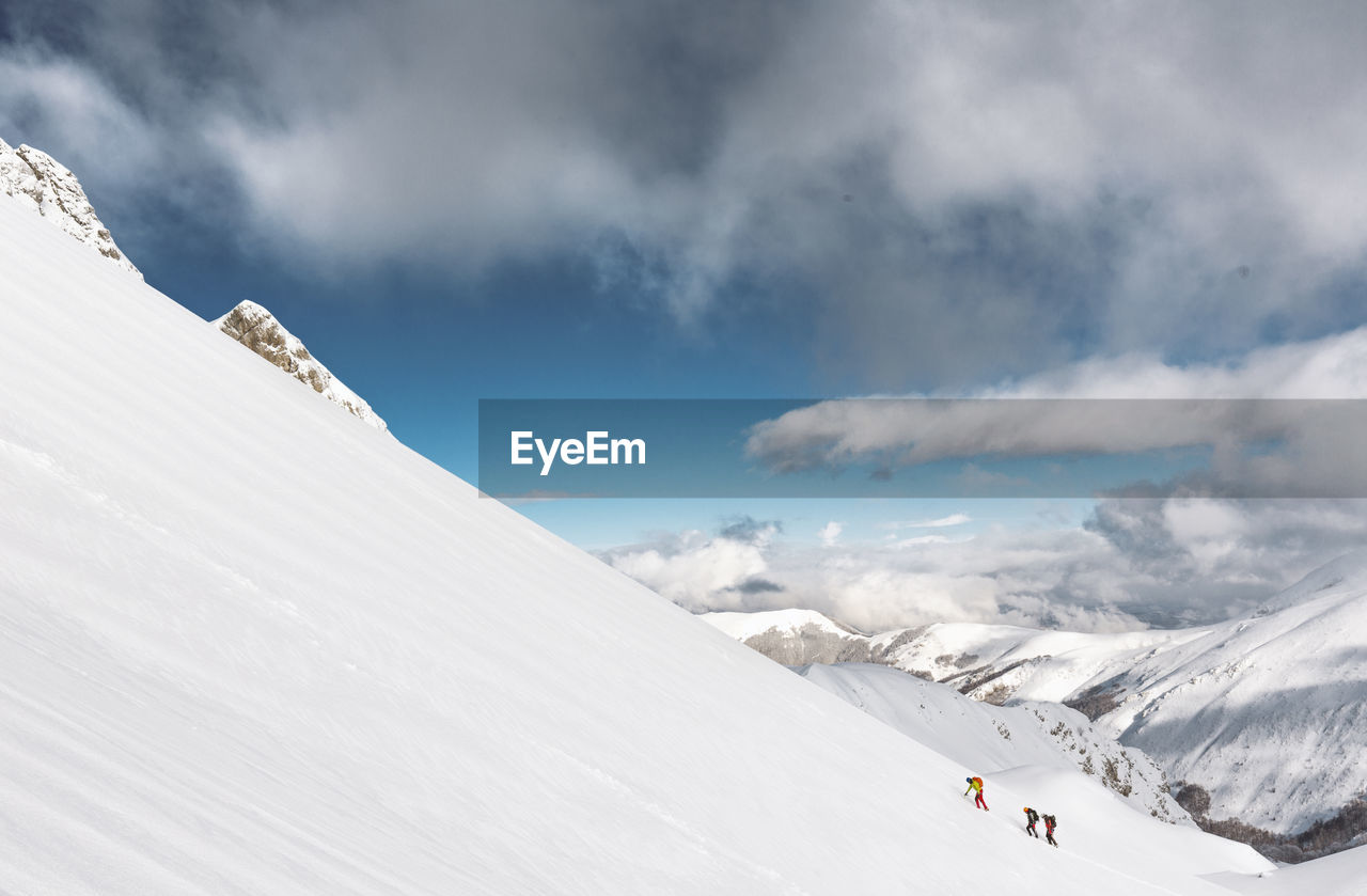 People climbing snowcapped mountains against sky