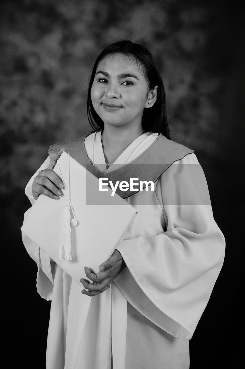 Portrait of young woman holding it's graduation cap and making her parents proud 