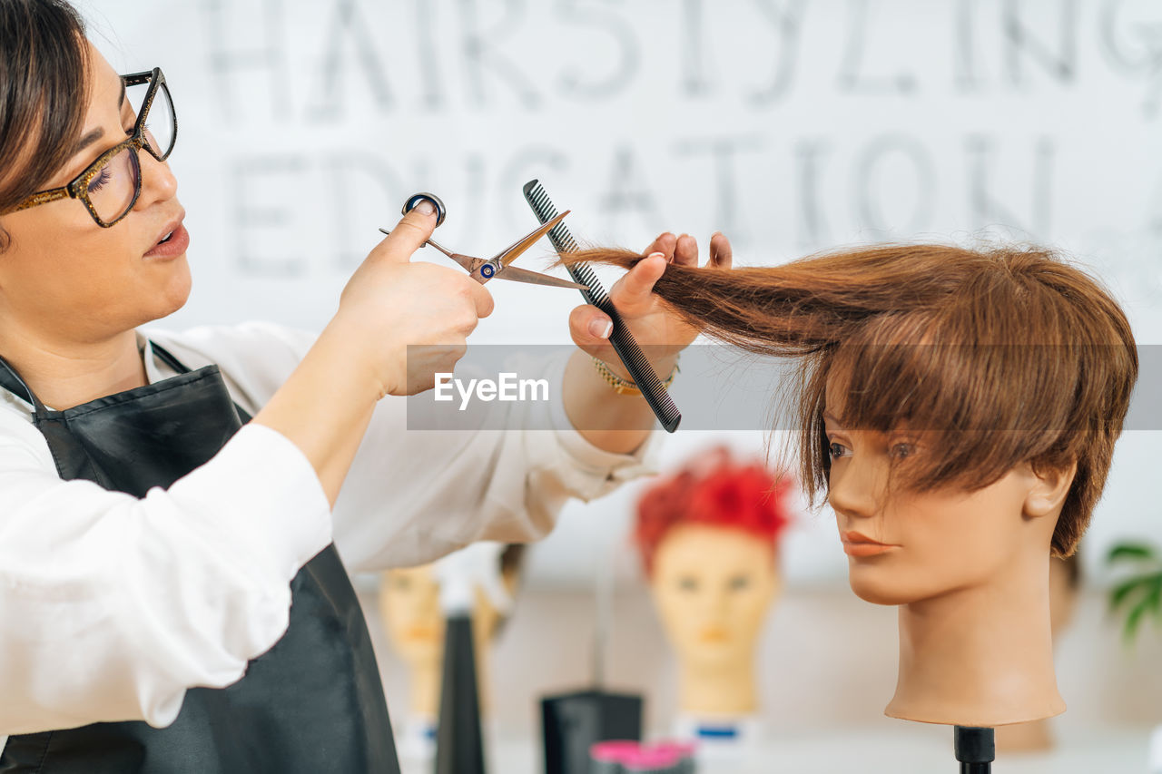 Haircutting education - hairstylist explaining haircutting techniques to students