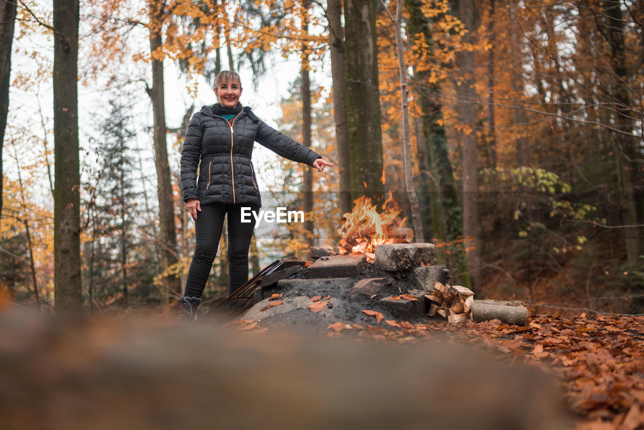 Woman standing by campfire in forest