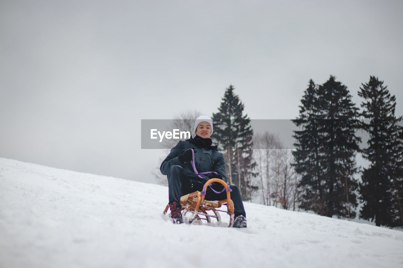 Teenager caught riding on a wooden sledge trying to adjust his direction with his hand 