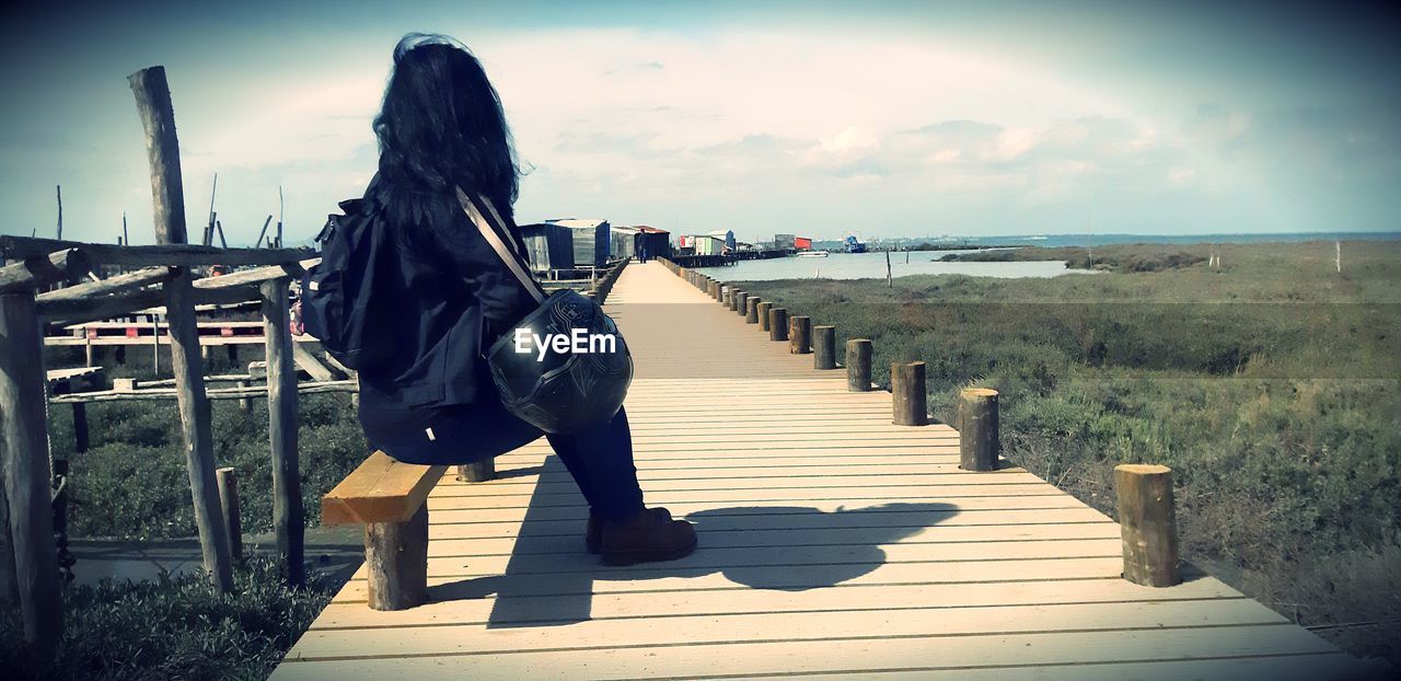 WOMAN WITH UMBRELLA WALKING ON SHORE AGAINST SKY