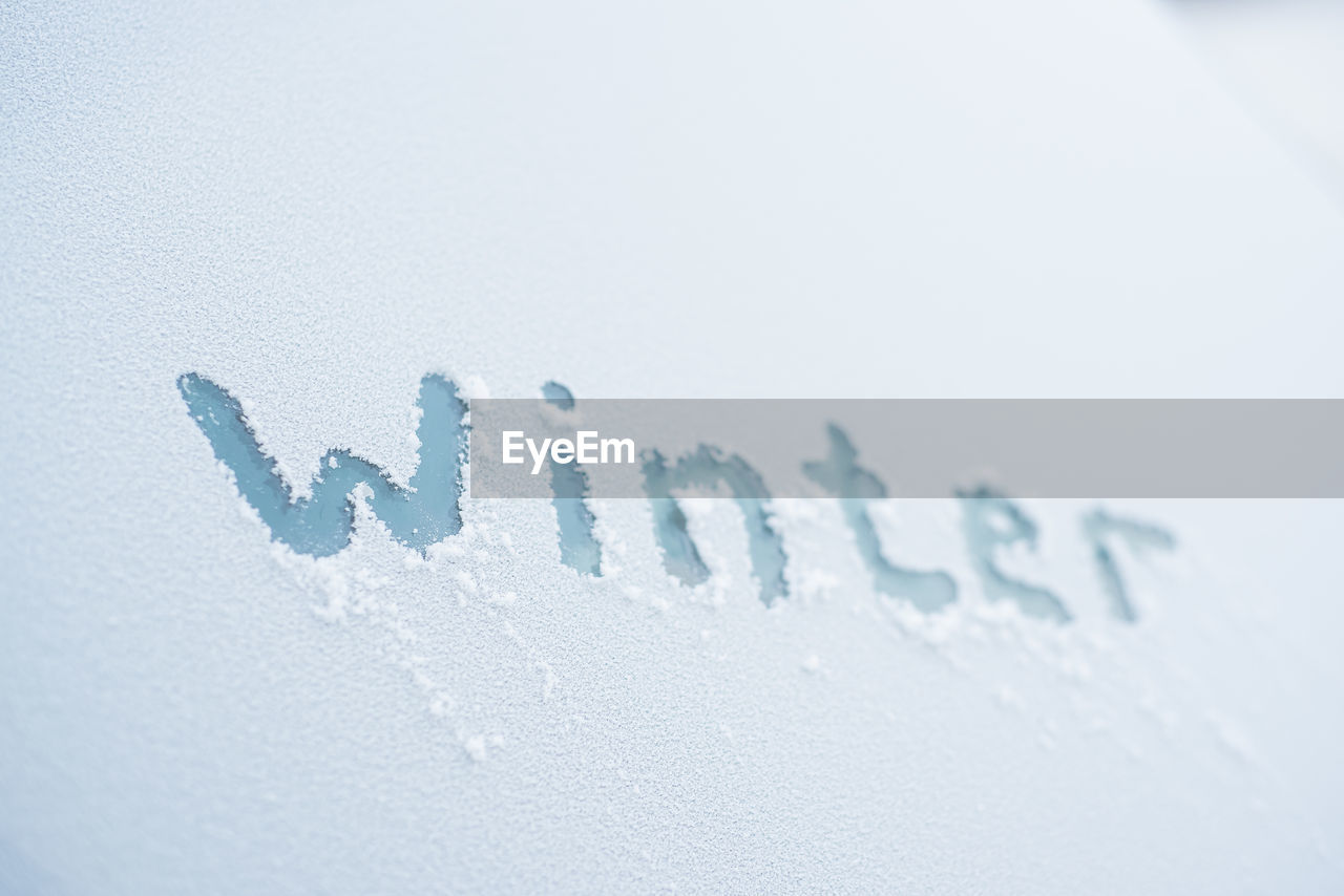 CLOSE-UP OF TEXT ON SNOW COVERED