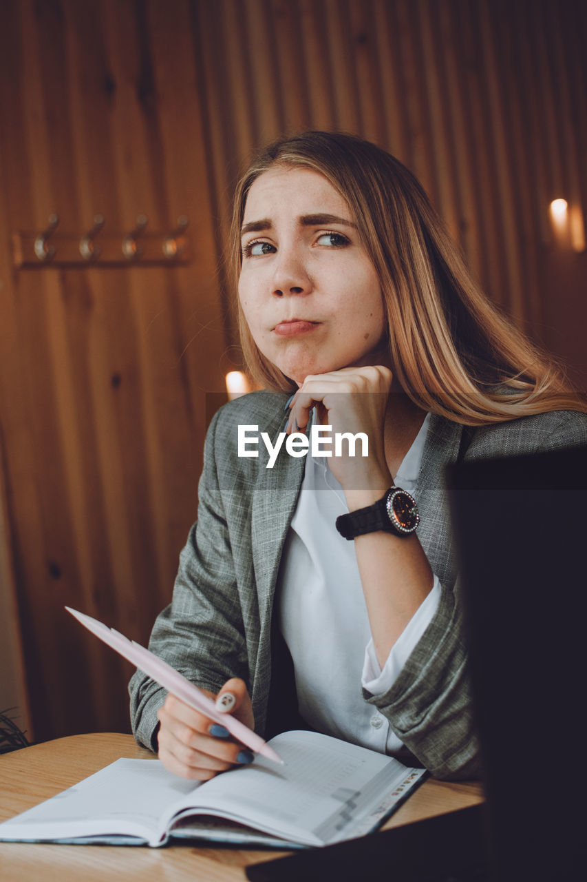 Young woman looking away while sitting on table