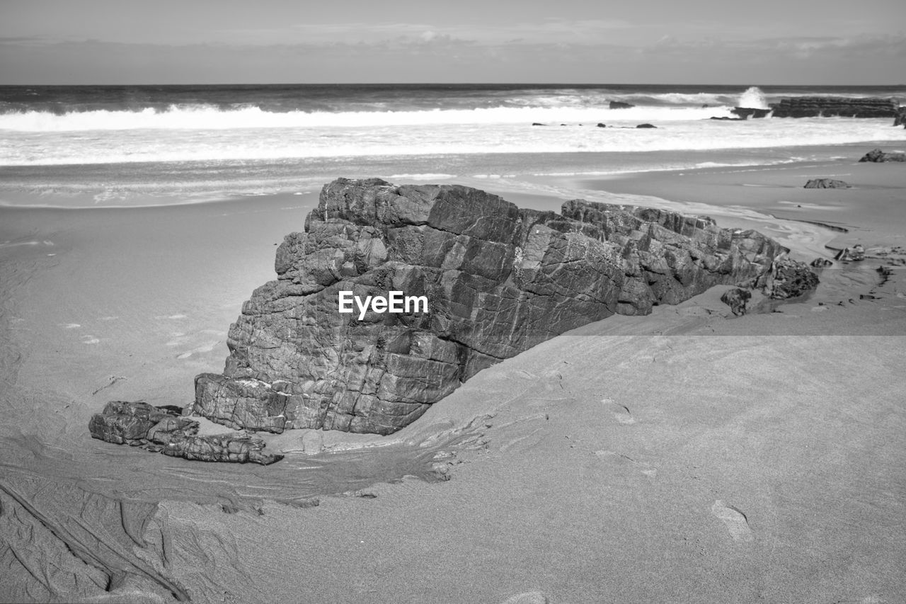 ROCKS ON BEACH AGAINST SKY