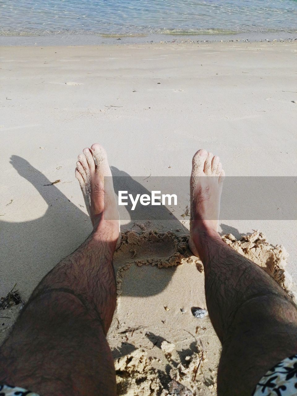 Low section of man relaxing at beach