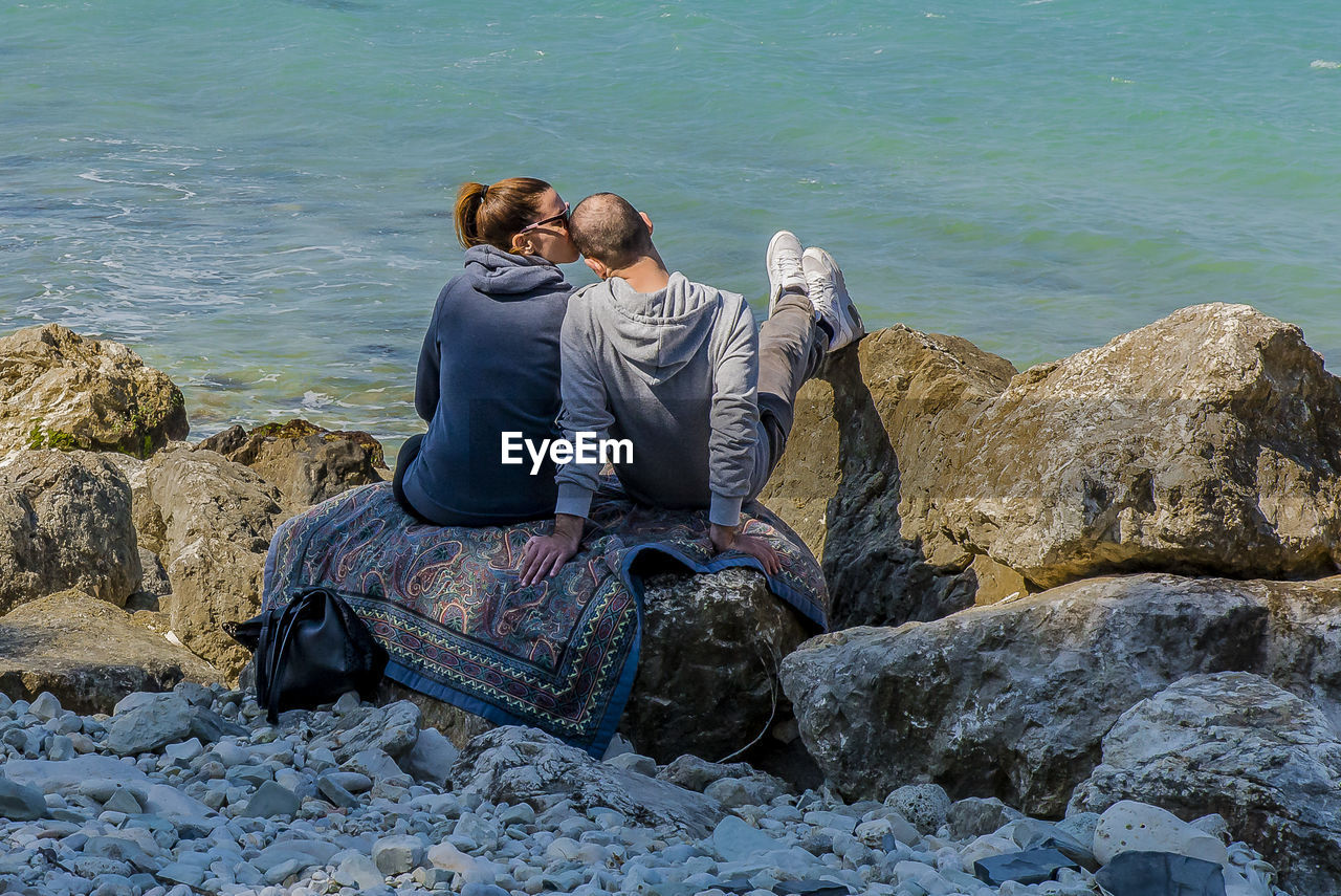 COUPLE SITTING ON BEACH