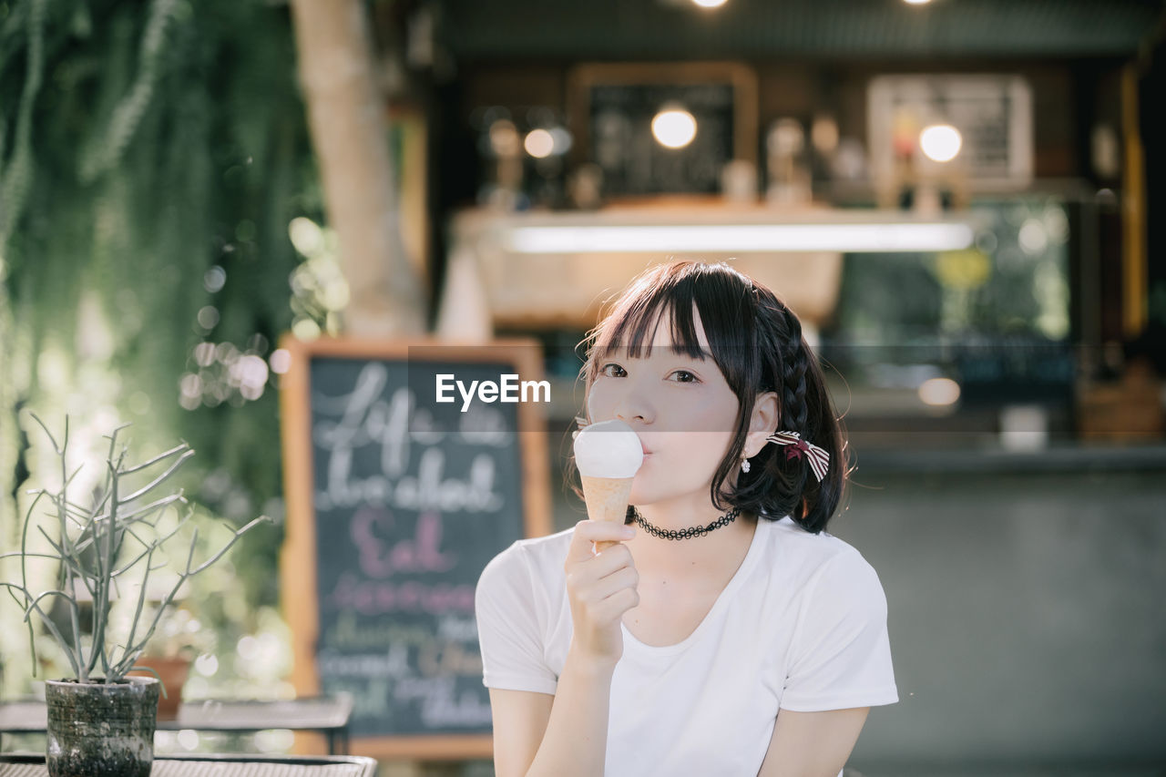 Portrait of young woman eating ice cream at restaurant