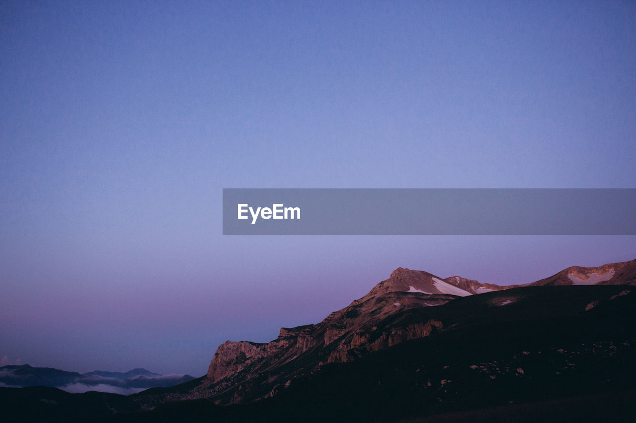 Scenic view of snowcapped mountains against clear blue sky