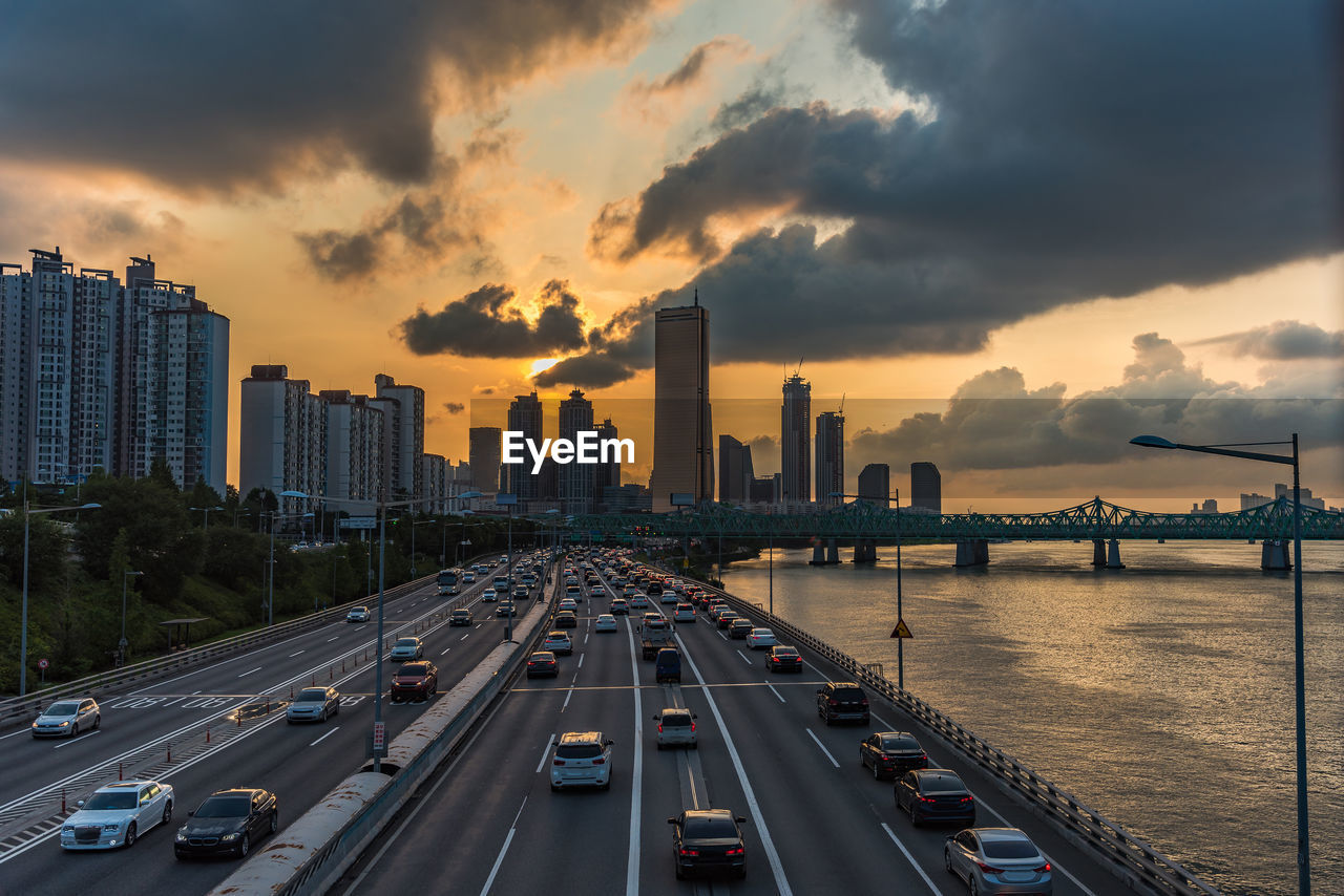 Panoramic view of city street and buildings against sky during sunset