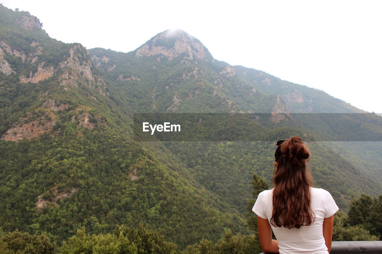 Rear view of woman looking at view of mountains against sky