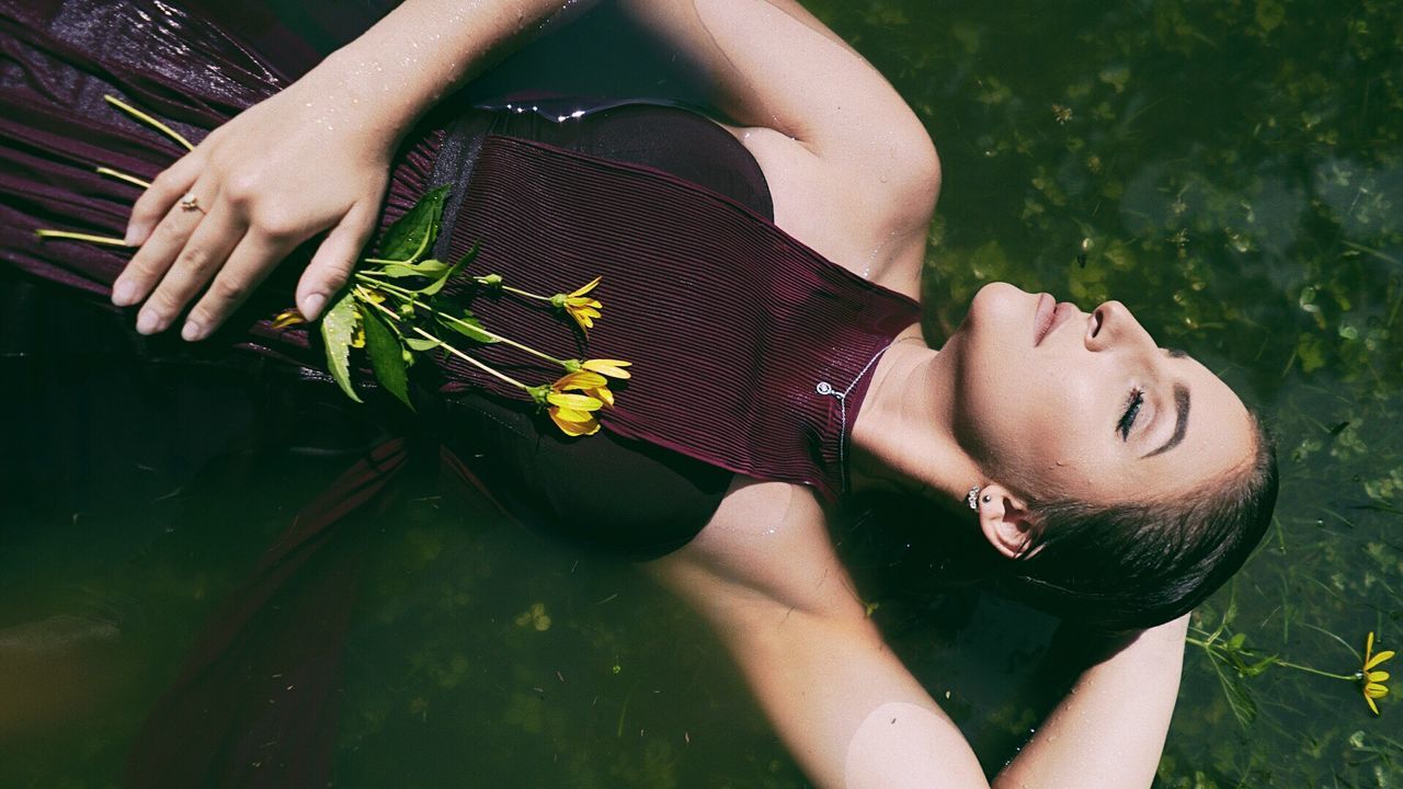 Directly above shot of young woman with flowers while relaxing in lake