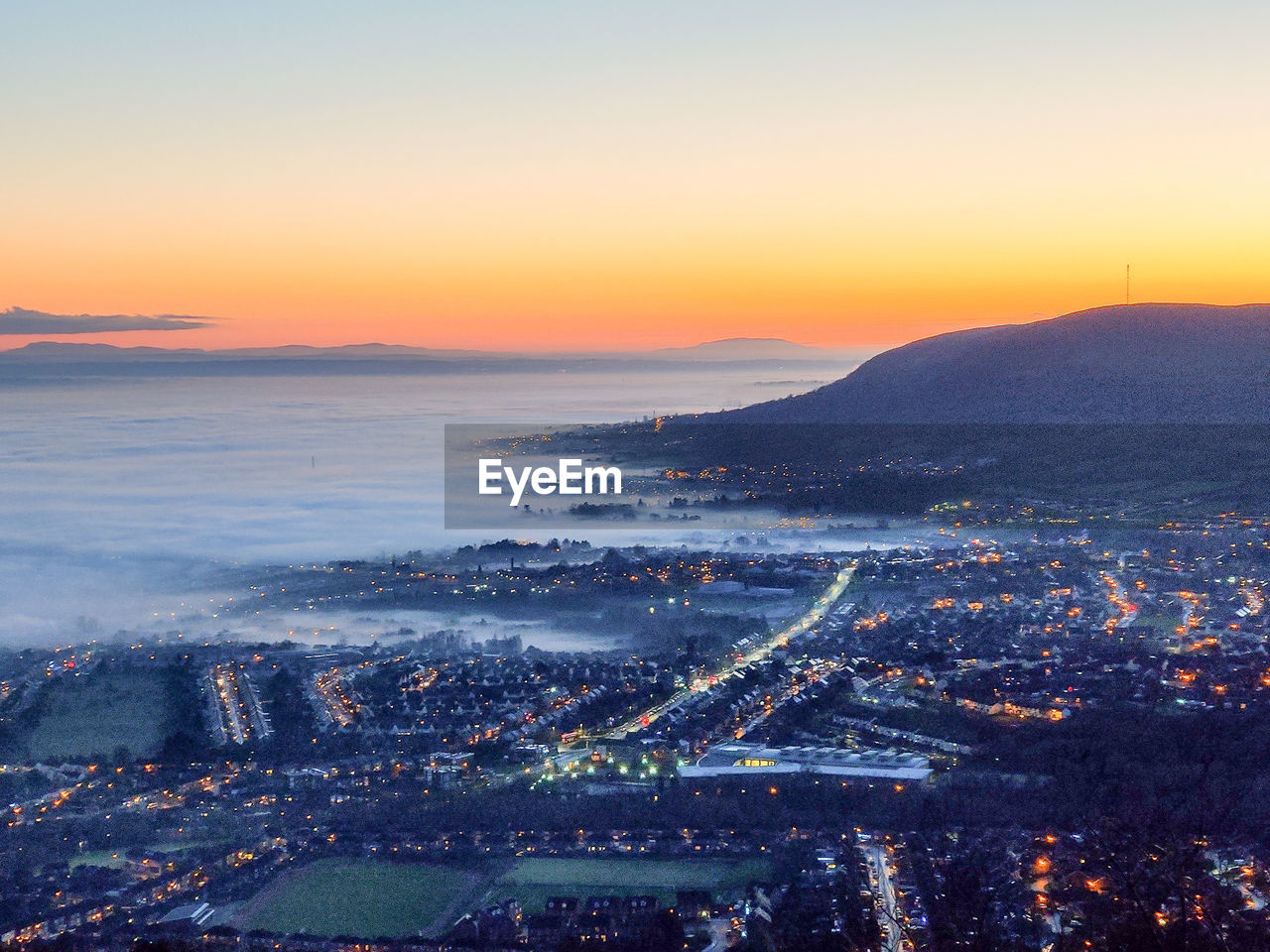 High angle view of belfast city during low fog, set against sky during sunset