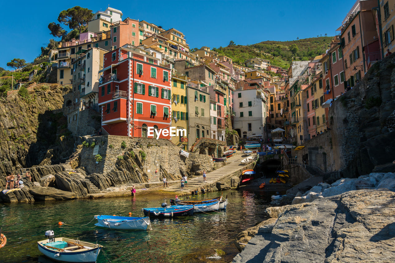 Boats moored on sea against buildings in town