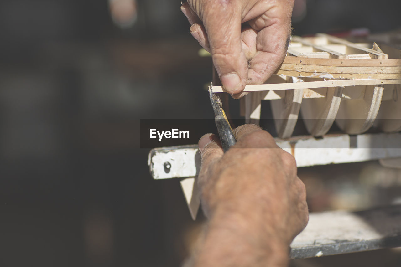 Close-up of man working on wooden boat model