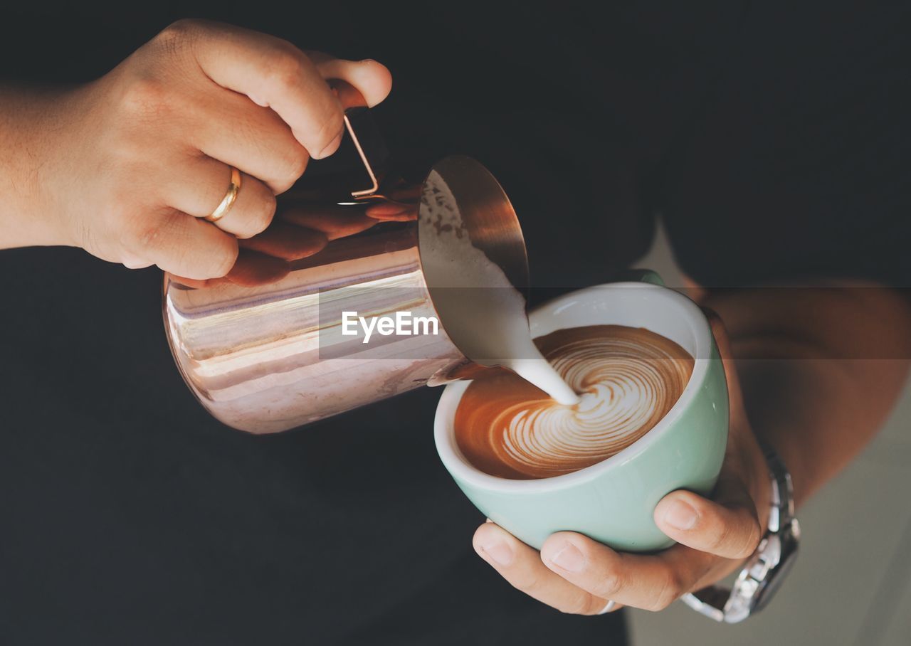 Midsection of woman pouring milk in coffee