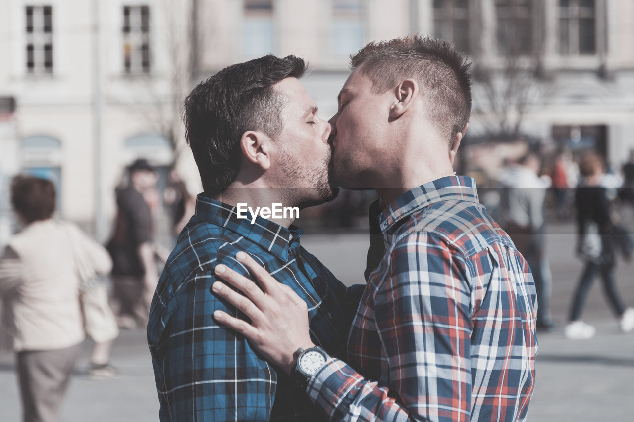 Side view of gay couple kissing on mouth in city