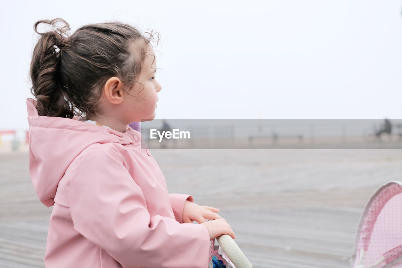 childhood, child, women, spring, female, one person, side view, pink, day, beach, clothing, nature, leisure activity, waist up, water, looking, lifestyles, copy space, hairstyle, person, sky, focus on foreground, emotion, outdoors, sea, toddler, sports, casual clothing, standing, happiness, baby, smiling, cute