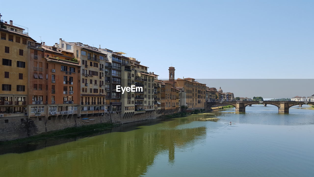 Bridge over river in city against clear sky