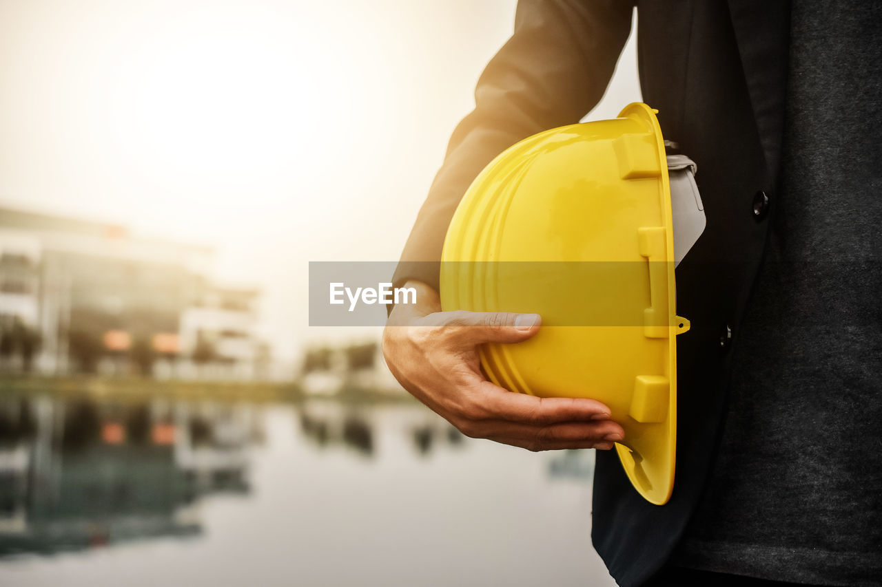 CLOSE-UP OF MAN HOLDING YELLOW CAMERA