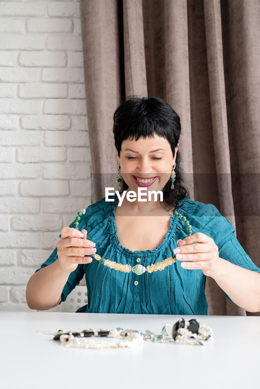Beautiful middle aged woman looking at the jewelery sitting at the table