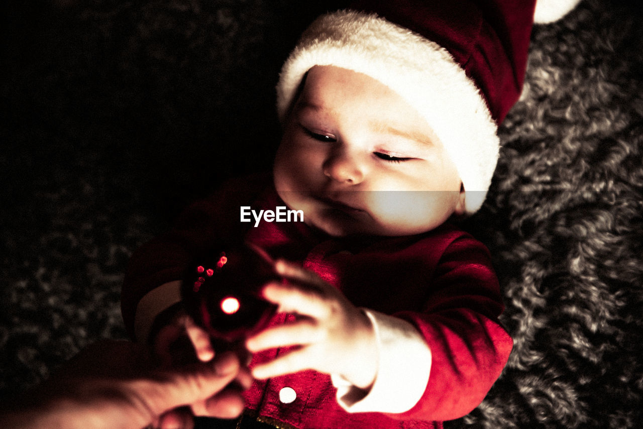 Cropped image of hand giving christmas ornament to cute baby boy