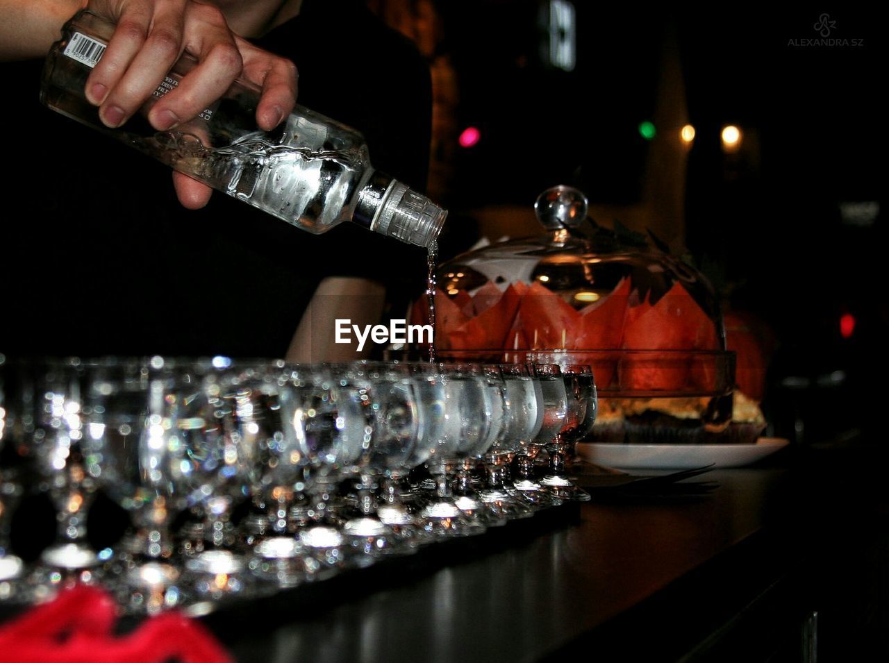 Close-up of man pouring alcohol in glasses on bar counter