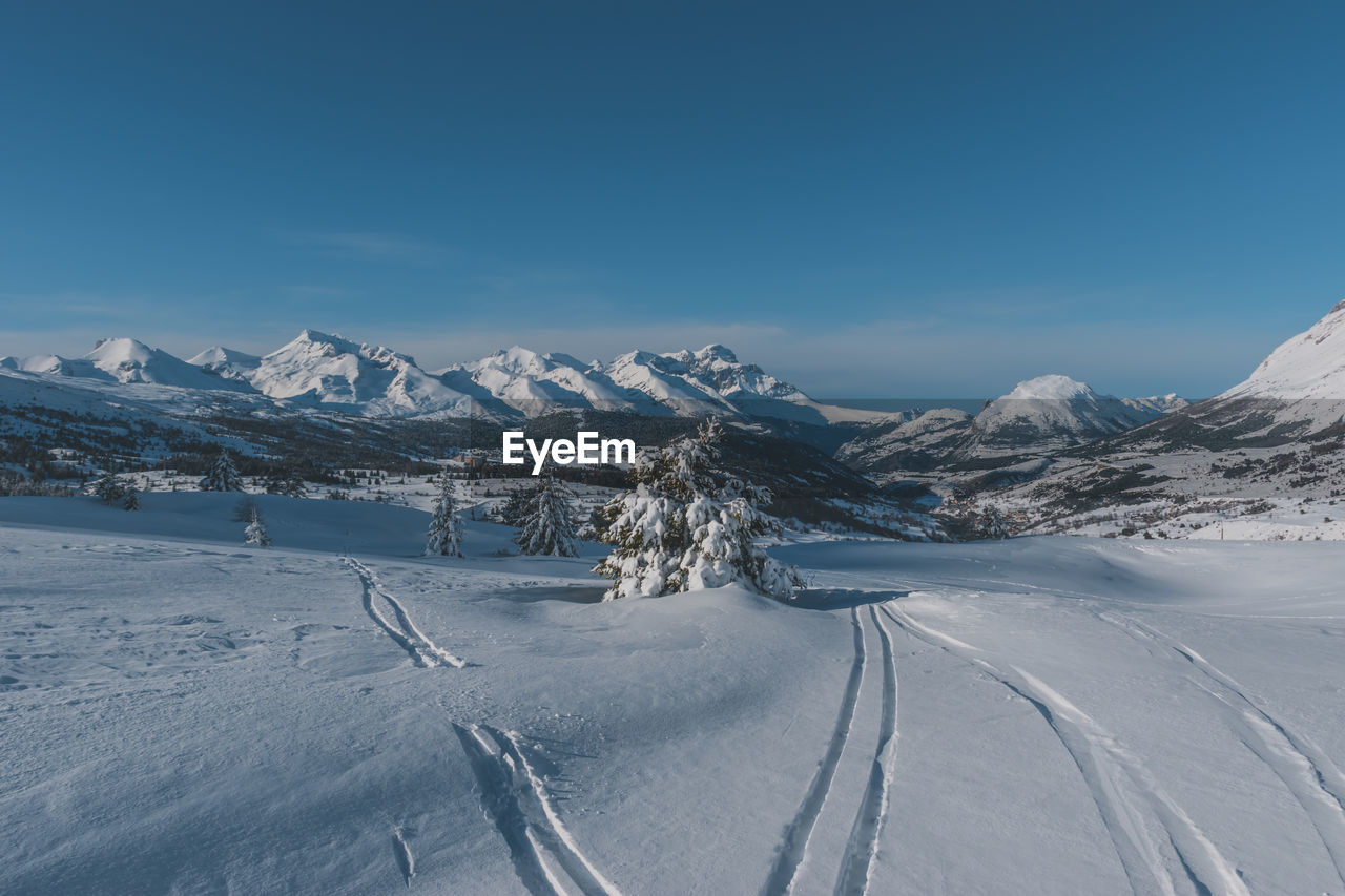 snow, winter, cold temperature, mountain, landscape, environment, scenics - nature, piste, sky, beauty in nature, mountain range, nature, snowcapped mountain, travel, blue, travel destinations, tranquil scene, no people, tranquility, winter sports, land, frozen, road, non-urban scene, transportation, ski touring, day, white, outdoors, ice, ski, clear sky, tourism, ski mountaineering, resort, ski equipment, cloud, copy space, tree, polar climate, idyllic