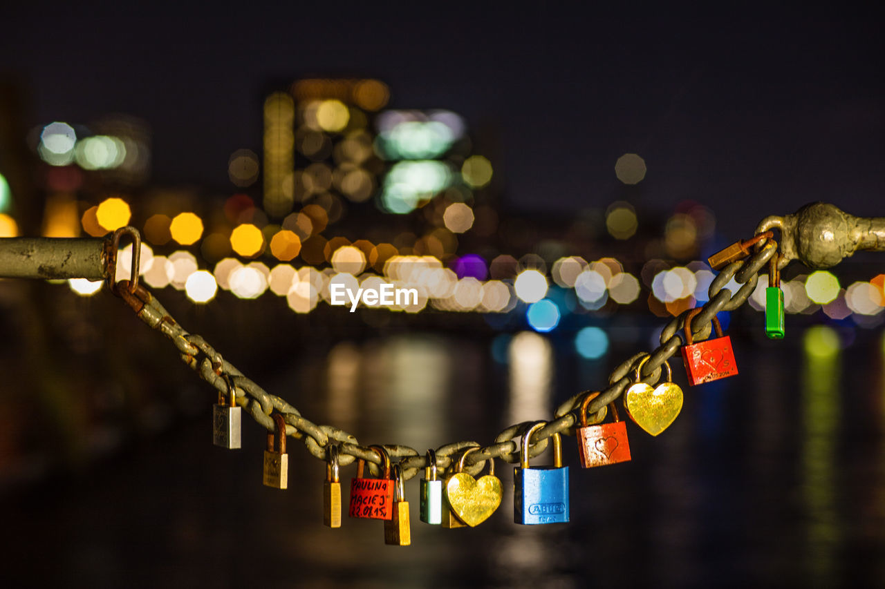 Close-up of colorful padlocks hanging at night