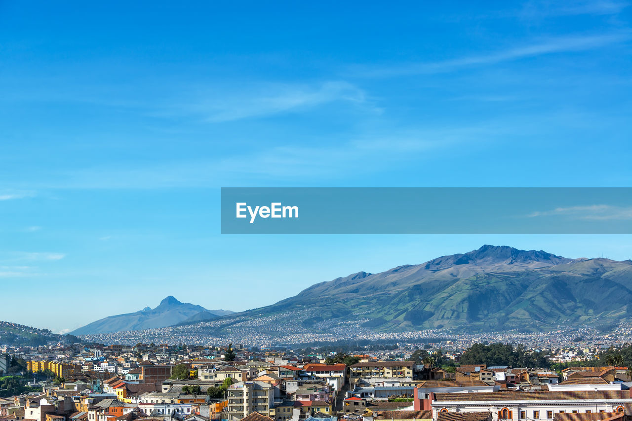 Cityscape by mountains against sky