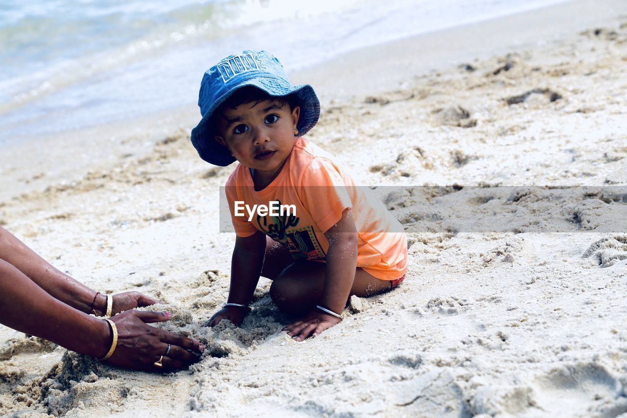 Portrait of boy playing with sand while sitting at beach