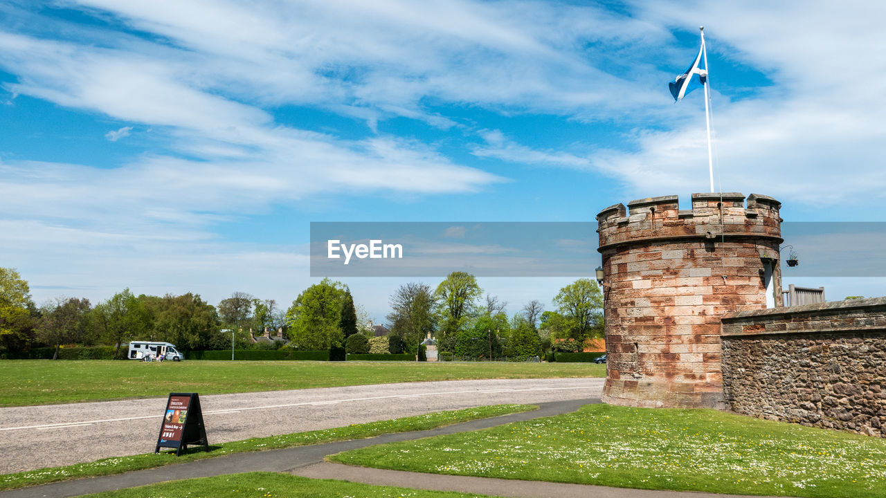 CASTLE ON FIELD BY BUILDING AGAINST SKY