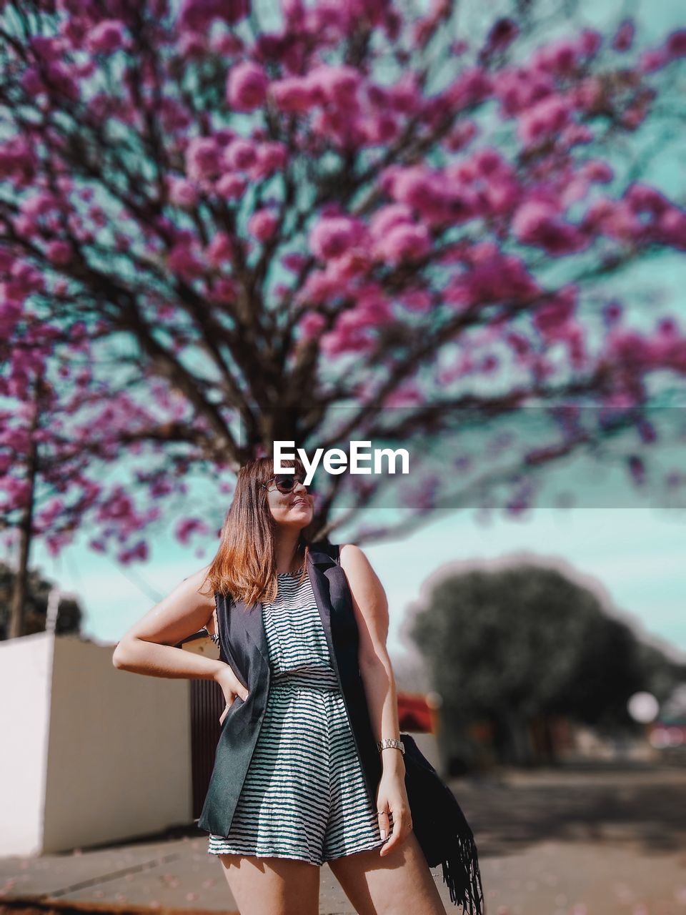 Young woman standing against flowering tree