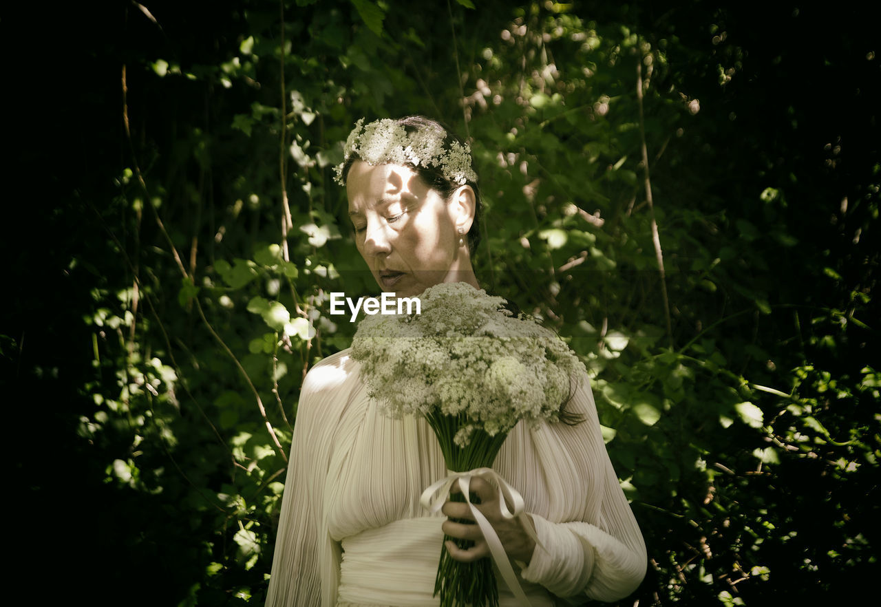 Woman in white blouse with flower bouquet and headband