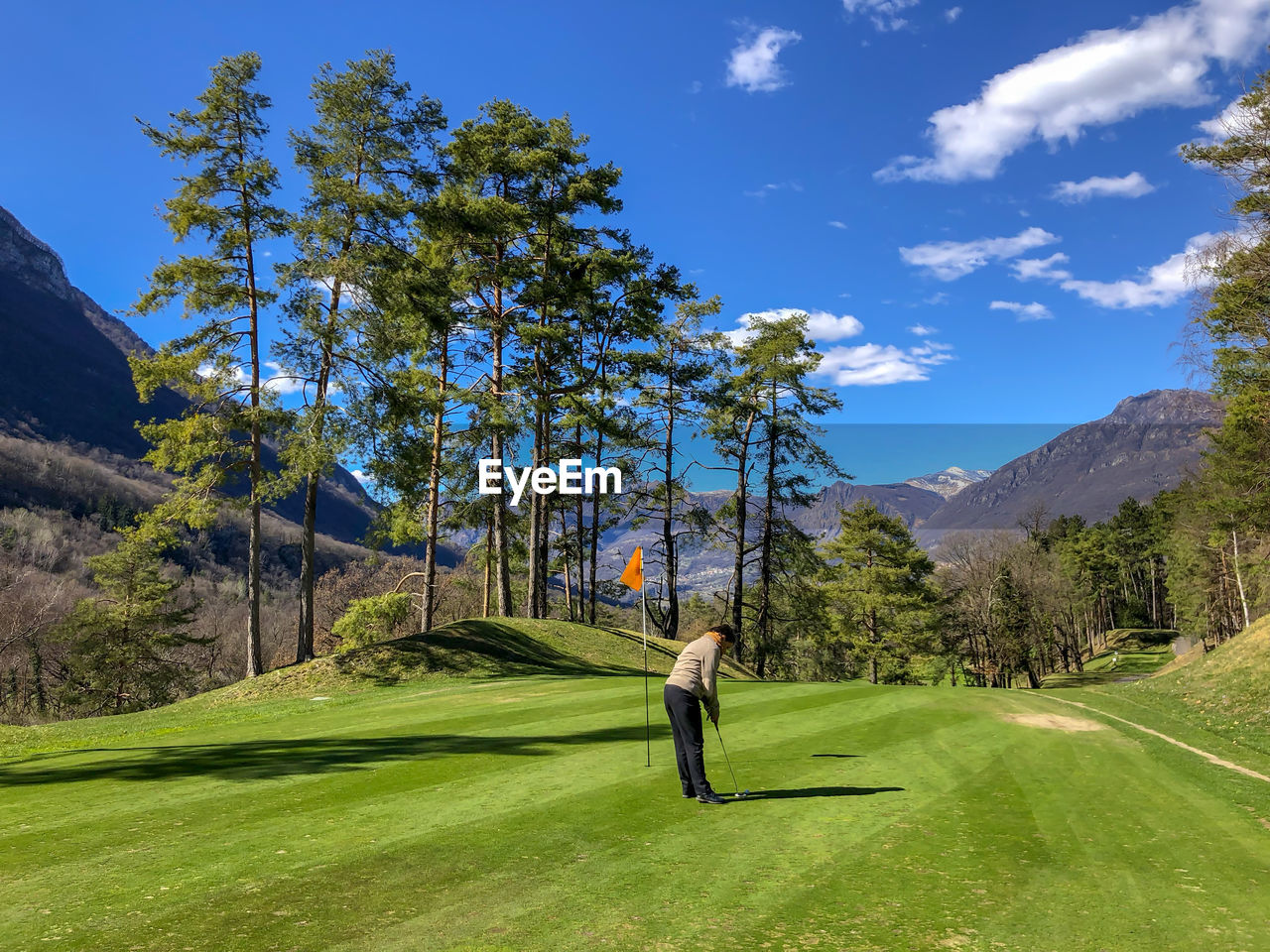 Golfer on putting green with mountain view in italy.