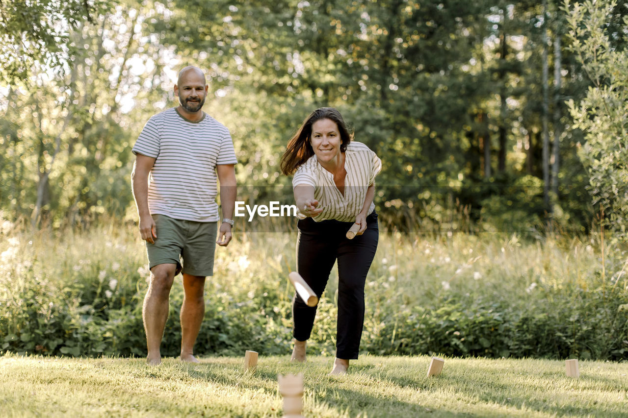 Smiling woman with male partner playing molkky in yard