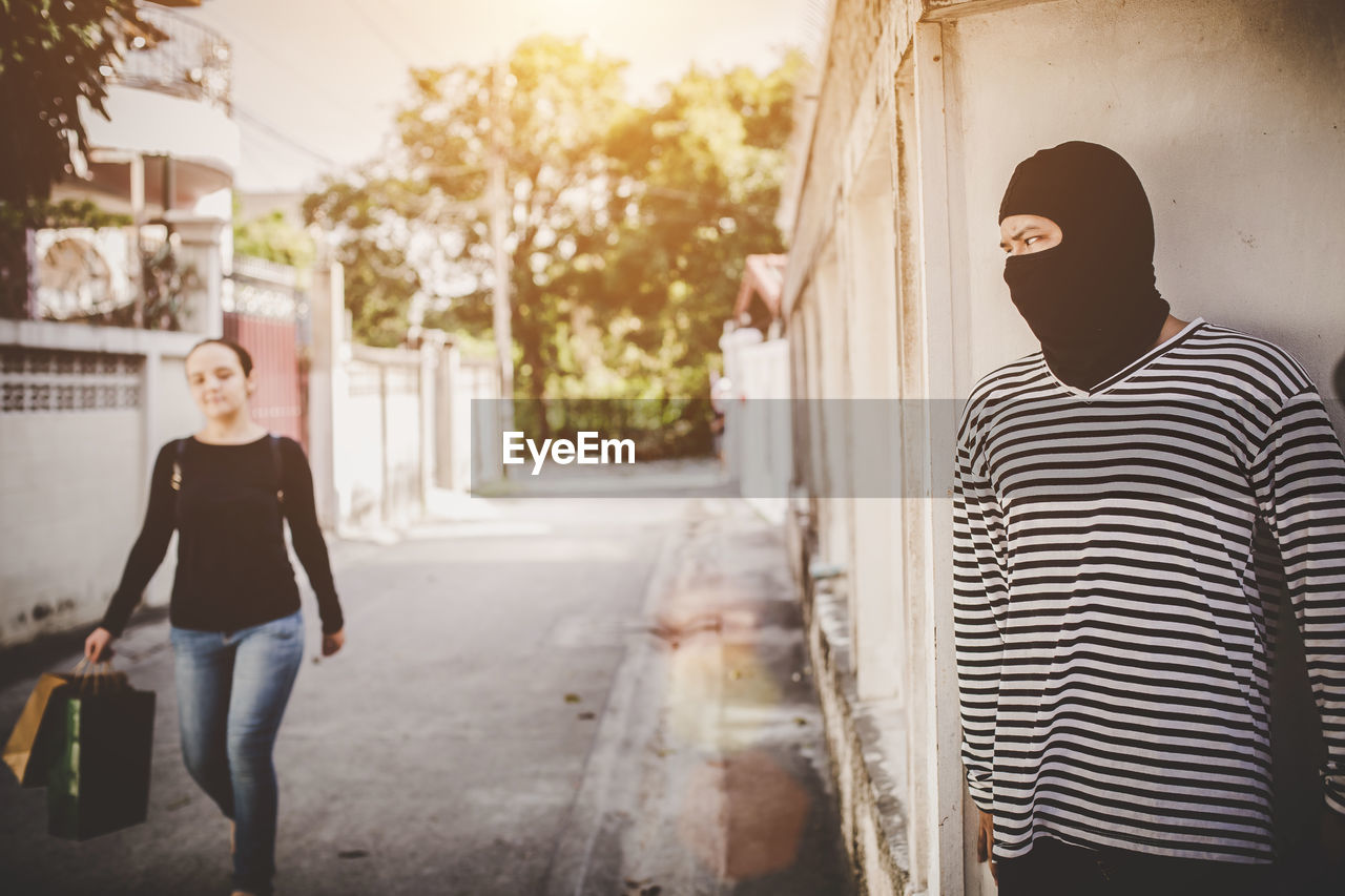 REAR VIEW OF MAN AND WOMAN WALKING OUTDOORS