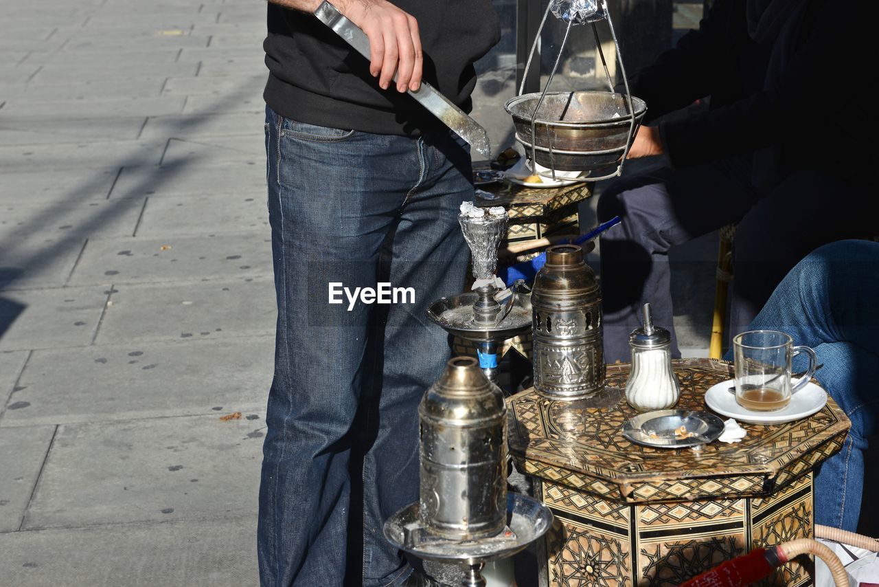 Midsection of man making drink while standing at sidewalk cafe