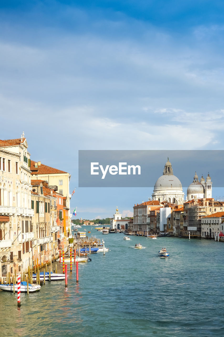 Grand canal by santa maria della salute in city against sky