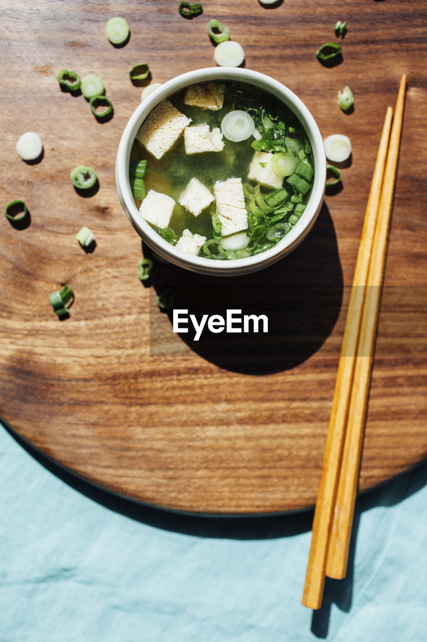 High angle view of soup bowl with chopsticks on serving board in commercial kitchen