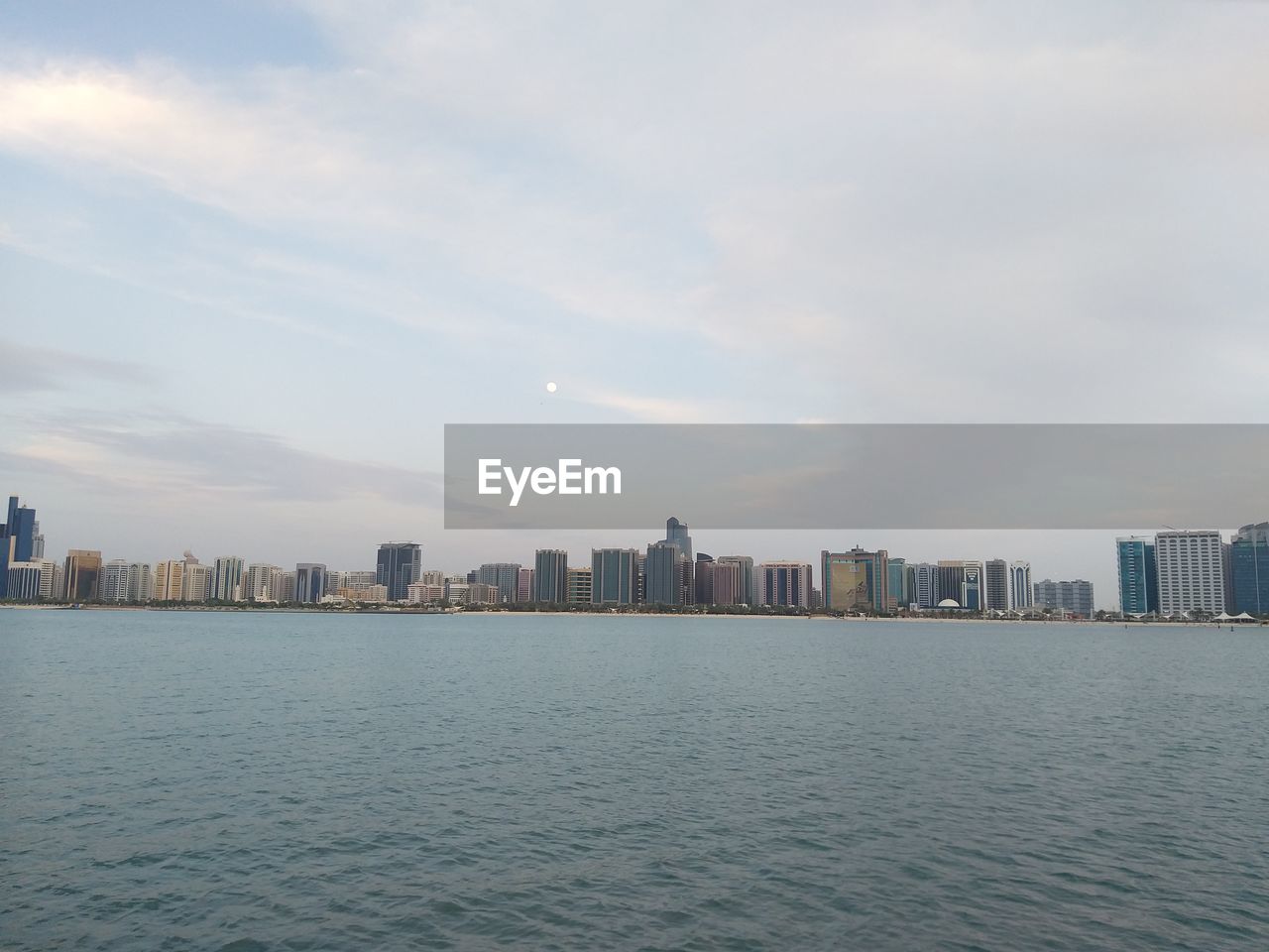 Sea by buildings in city against sky