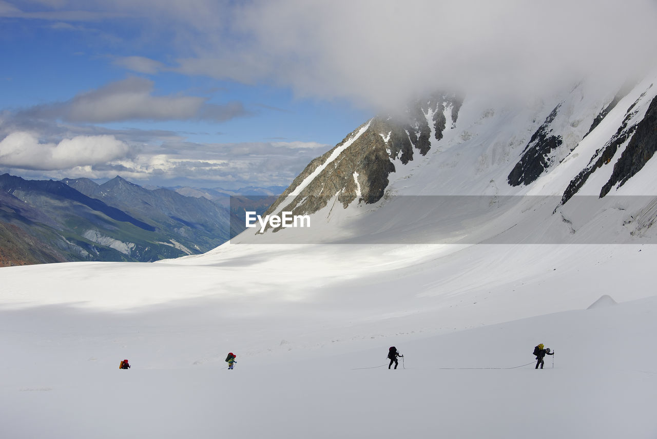 People hiking on snowcapped mountain against sky