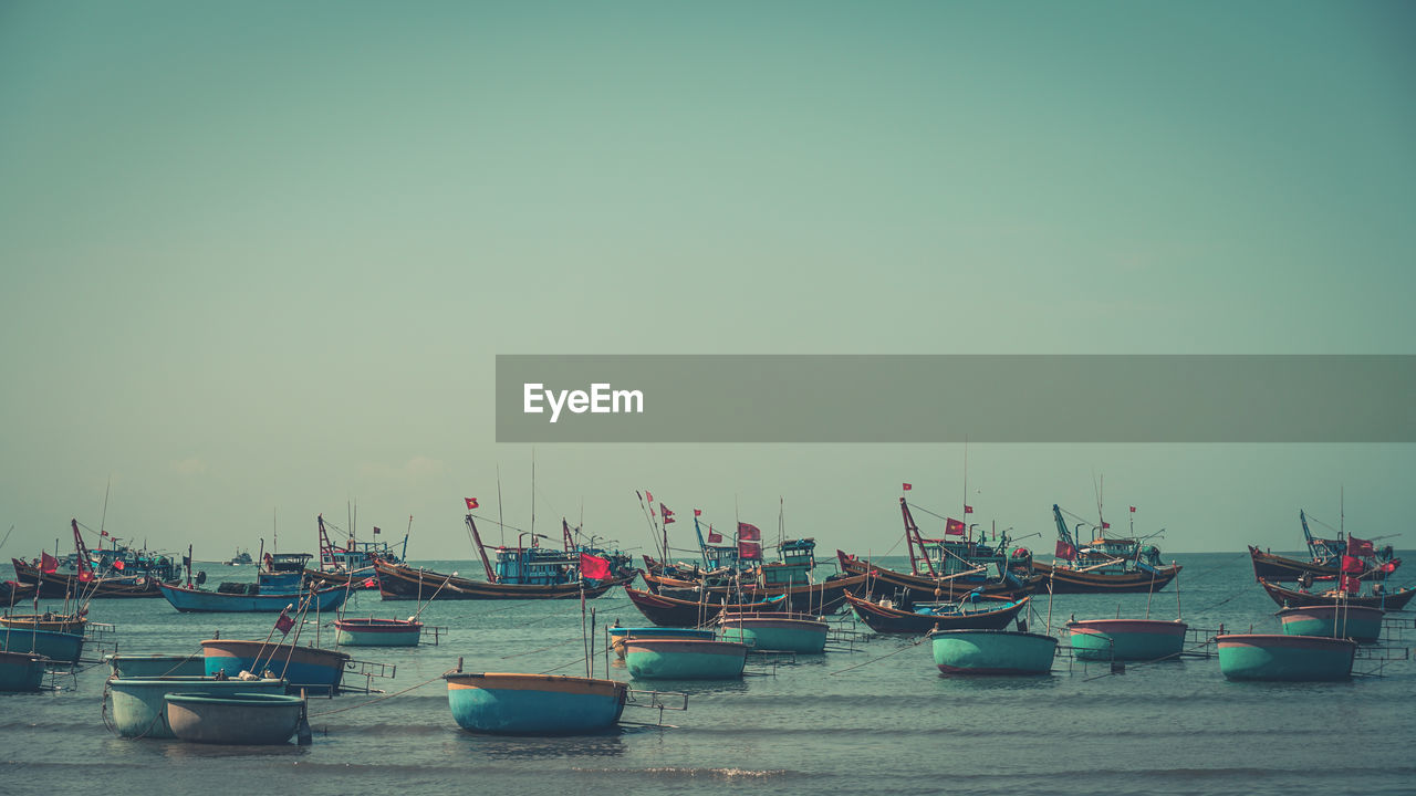 SAILBOATS MOORED IN SEA AGAINST SKY