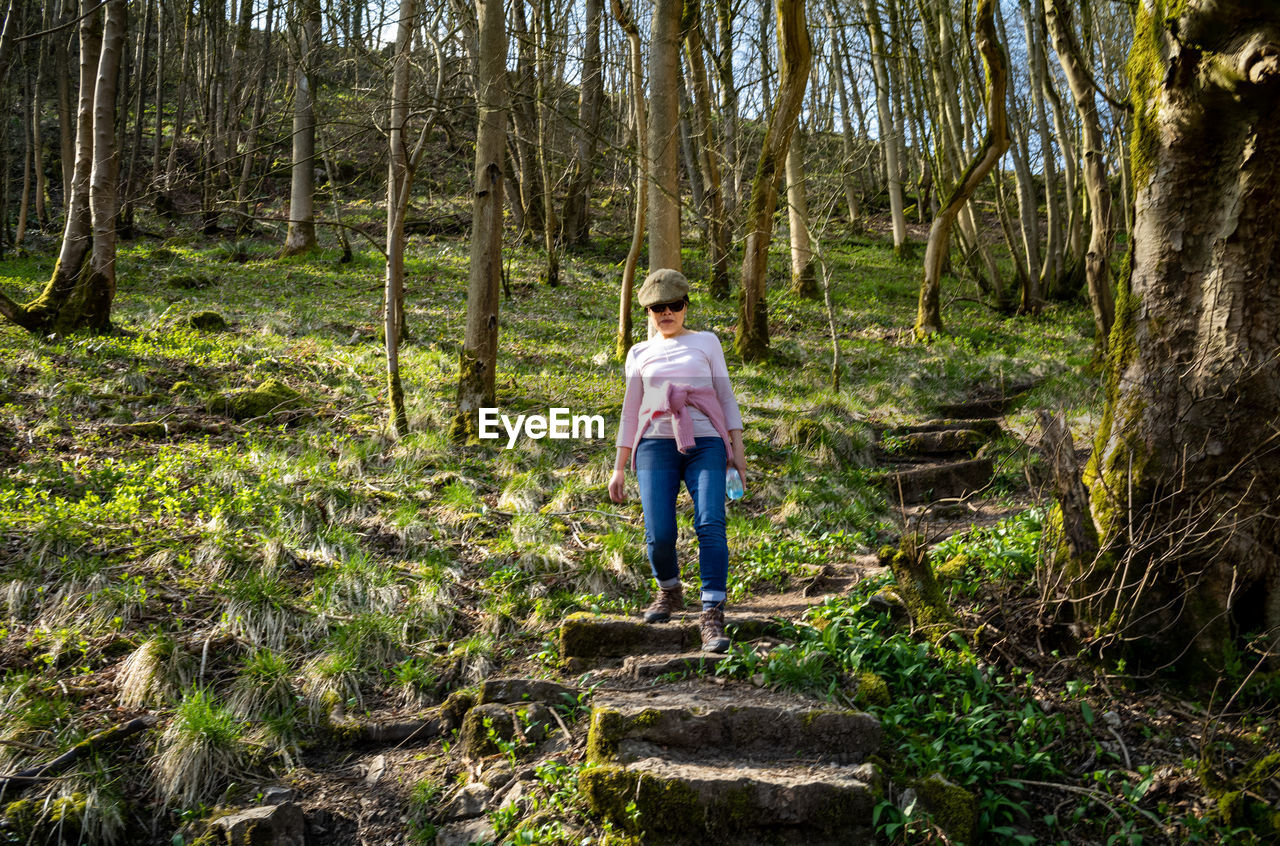 A vietnamese woman walks down a steep forest path in the peak district, uk