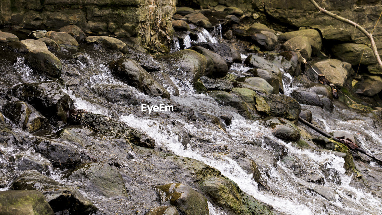 HIGH ANGLE VIEW OF STREAM FLOWING THROUGH ROCK