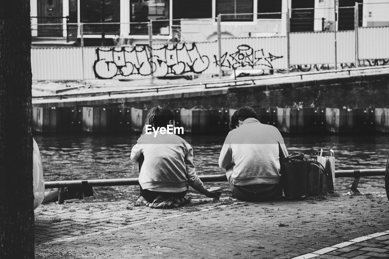 REAR VIEW OF MEN SITTING IN LAKE