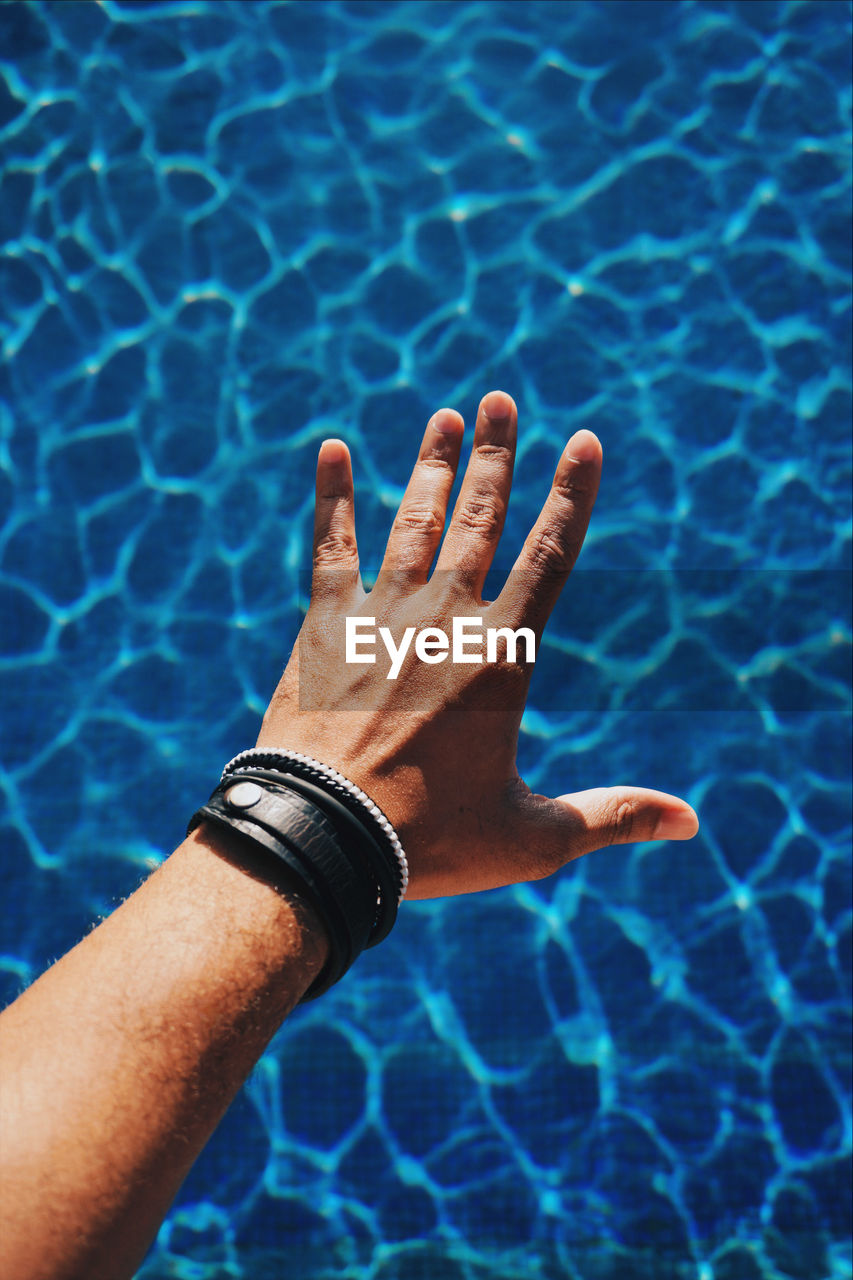 Cropped hand of man over swimming pool