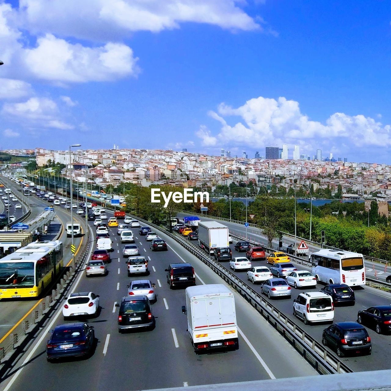 HIGH ANGLE VIEW OF VEHICLES ON ROAD ALONG BUILDINGS