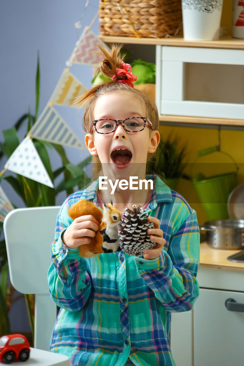 Portrait of girl holding toys at home